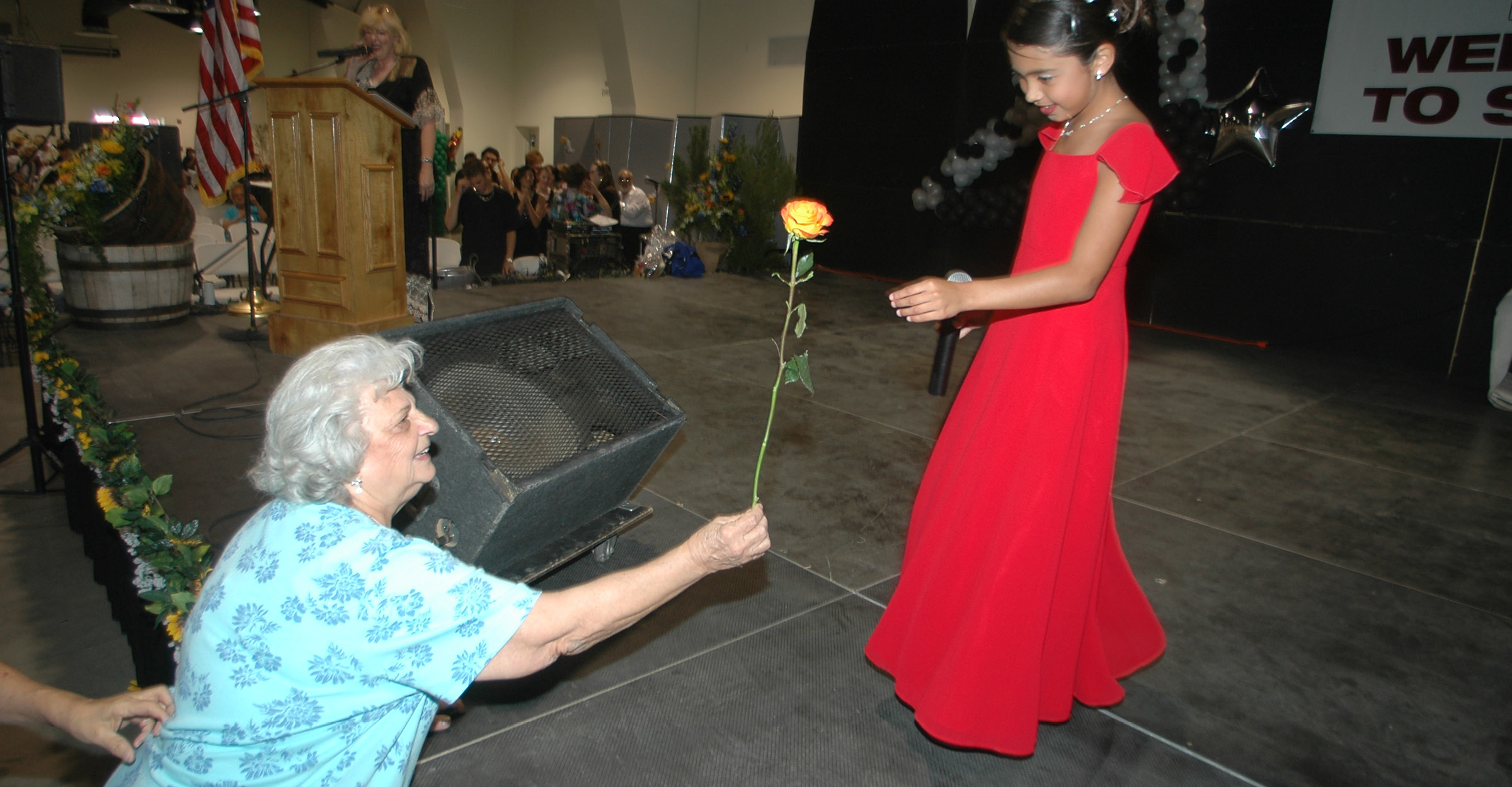 Senior giving a rose to a young perfomer